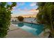 Tranquil pool with custom water feature surrounded by lush tropical landscaping at sunset at 7608 Antilla St, Tampa, FL 33625