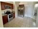 Well-lit kitchen with stainless steel appliances, wood cabinets, tile flooring, and a pantry at 8608 Twin Farms Pl, Tampa, FL 33635