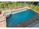 Aerial view of screened in in-ground pool and spa with brick surround and greenery at 13310 Waterford Run Dr, Riverview, FL 33569