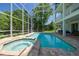 A screened-in pool and jacuzzi are surrounded by brick and landscaping at 13310 Waterford Run Dr, Riverview, FL 33569