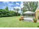 Spacious backyard featuring a grill under a pergola, tropical landscaping, and screened-in pool at 14119 Stonegate Dr, Tampa, FL 33624
