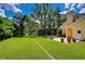 Expansive backyard featuring a manicured lawn, lush landscaping, a screened-in pool, and mature trees at 14119 Stonegate Dr, Tampa, FL 33624