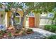 Close-up of the front entrance featuring an orange double door, arched windows, and tasteful landscaping at 14119 Stonegate Dr, Tampa, FL 33624