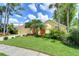 Charming single-story home featuring a lush green lawn, bright orange front door, and mature tropical landscaping at 14119 Stonegate Dr, Tampa, FL 33624
