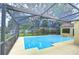 A screened-in pool with clear blue water, a yellow patio, and trees surrounding the pool at 14119 Stonegate Dr, Tampa, FL 33624