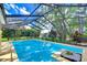 Inviting pool with screened enclosure, surrounded by lush greenery and featuring a small decorative planter at 14119 Stonegate Dr, Tampa, FL 33624