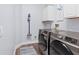 Laundry room with stainless washer and dryer, utility sink, and storage cabinets at 14521 Mirasol Manor Ct, Tampa, FL 33626