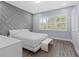 Modern main bedroom with light gray accent wall, hardwood floors, and bright sunny windows at 14521 Mirasol Manor Ct, Tampa, FL 33626