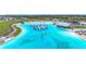 Breathtaking aerial shot of resort-style pool with paddle boarders in crystal clear blue water near community homes at 17228 Holly Well Ave, Wimauma, FL 33598