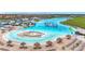 Stunning aerial view of a lagoon with white sand beaches, an inflatable water park, and thatched umbrellas at 17228 Holly Well Ave, Wimauma, FL 33598