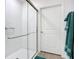 Bathroom featuring a tiled walk-in shower with glass door, white door, and fresh green towels at 17228 Holly Well Ave, Wimauma, FL 33598