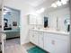 Bathroom featuring double sinks with white cabinets, a large mirror, and a doorway to the bedroom at 17228 Holly Well Ave, Wimauma, FL 33598