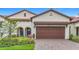 Charming exterior view of the home featuring a brick driveway and two-car garage at 17228 Holly Well Ave, Wimauma, FL 33598