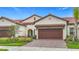 Charming home featuring a brick driveway, well-manicured landscaping, and a two-car garage at 17228 Holly Well Ave, Wimauma, FL 33598