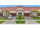 Aesthetic single-Gathering home featuring a red tile roof, paver driveway, lush landscaping, and an attached two-car garage at 17228 Holly Well Ave, Wimauma, FL 33598