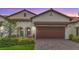 Charming home featuring a brick driveway, a two-car garage, and lush landscaping with a stucco facade and tile roof at 17228 Holly Well Ave, Wimauma, FL 33598