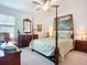 Primary bedroom suite featuring a four-poster bed, dresser, and painting at 17228 Holly Well Ave, Wimauma, FL 33598