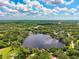 Overhead view of a house nestled near a lake, embraced by verdant trees and clear skies at 17301 Estes Rd, Lutz, FL 33548