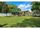Beautifully landscaped backyard with well-manicured lawn, mature trees, screened porch, and privacy fence at 17301 Estes Rd, Lutz, FL 33548