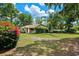 Charming single-story home with a well-manicured lawn, lush trees, and vibrant bougainvillea bush at 17301 Estes Rd, Lutz, FL 33548