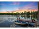Picturesque lake view featuring a boat dock, a small motor boat, and a serene sunset reflecting off the water at 17301 Estes Rd, Lutz, FL 33548