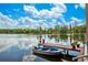Beautiful lake view featuring a boat dock, a small motor boat, and a calm, reflective waterscape at 17301 Estes Rd, Lutz, FL 33548