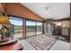 Bright living room featuring lake views, large windows, wood paneling, and an outdoor deck at 17301 Estes Rd, Lutz, FL 33548