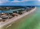 Sweeping aerial view of a coastal city featuring beachfront properties, a sandy beach, and turquoise waters at 19700 Gulf Blvd # 403, Indian Shores, FL 33785