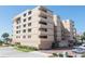 Exterior view of a multi-story building with neutral-toned brick, balconies, manicured landscaping, and a paved driveway at 19700 Gulf Blvd # 403, Indian Shores, FL 33785