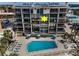 Poolside view of condo building with sun loungers and clear blue water surrounded by palm trees and manicured landscaping at 19700 Gulf Blvd # 403, Indian Shores, FL 33785