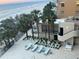 Relaxing pool area featuring palm trees, lounge chairs, tables, and a view of the beach at 19700 Gulf Blvd # 403, Indian Shores, FL 33785