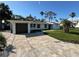 Charming single-story home with a beautifully paved driveway and lush tropical landscaping under a clear, sunny sky at 204 162Nd Ave, Redington Beach, FL 33708