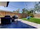 Backyard area with a barbecue grill, patio, white rocks, artificial grass, blue chairs and a wooden fence at 2488 Del Rio Way, Dunedin, FL 34698