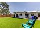 Backyard with lush artificial turf, a white house, a grilling area, outdoor seating, and a wooden privacy fence at 2488 Del Rio Way, Dunedin, FL 34698
