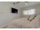 Cozy bedroom features a plush white bed, a wall-mounted television, and a window offering natural light at 2488 Del Rio Way, Dunedin, FL 34698