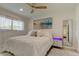 Inviting bedroom with soft white bedding, beach-themed art, a ceiling fan, and accent lighting in the nightstand at 2488 Del Rio Way, Dunedin, FL 34698