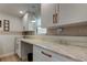 Bright laundry room featuring white cabinets, a marble countertop, and stylish light fixtures at 2488 Del Rio Way, Dunedin, FL 34698