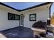 Outdoor patio featuring a grill, black trim windows, a glass door and a security camera on a white house at 2488 Del Rio Way, Dunedin, FL 34698