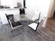 This dining room features a modern glass table, wooden flooring, and modern chairs at 25417 Lexington Oaks Blvd, Wesley Chapel, FL 33544