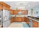Well-lit kitchen with wooden cabinetry, stainless steel appliances, granite countertops and a blue patterned rug at 2558 Arborwood Dr, Valrico, FL 33596