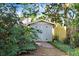 Backyard storage shed with double doors and painted a neutral color with surrounding landscape and a stone walkway at 2558 Arborwood Dr, Valrico, FL 33596