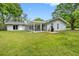 Backyard features green lawn, mature trees, and covered patio, providing a peaceful outdoor retreat at 346 Ranch Rd, Tarpon Springs, FL 34688