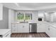 Bright kitchen featuring white cabinets, stainless steel appliances, and a view of the backyard through a window above the sink at 346 Ranch Rd, Tarpon Springs, FL 34688