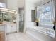 Bright bathroom with a soaking tub under a window, decorative chandelier, and walk-in shower at 3625 Gaviota Dr, Ruskin, FL 33573