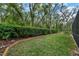 A well-manicured backyard with a green lawn, landscaping beds, and mature trees along the fence line at 5806 Terncrest Dr, Lithia, FL 33547