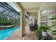 A covered patio featuring an outdoor kitchen, ceiling fan, and comfortable seating overlooking the pool area at 5806 Terncrest Dr, Lithia, FL 33547