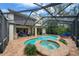 A luxurious screened-in pool and spa area with brick paving and comfortable outdoor seating under a blue sky at 5806 Terncrest Dr, Lithia, FL 33547