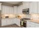 Well-lit kitchen with white cabinets, granite countertops, and stainless steel appliances at 600 Reserve Ln, Dunedin, FL 34698