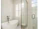 A modern bathroom featuring marble walls, a soaking tub, a glass enclosed shower, and natural light at 600 Reserve Ln, Dunedin, FL 34698