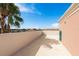 Wide rooftop terrace showcases distant building and blue sky with green hose for plants at 600 Reserve Ln, Dunedin, FL 34698